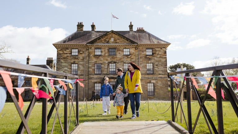 Young family walking to the front lawn in front of Ormesby Hall